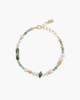 Overhead view of a beaded bracelet with green moss agate, strawberry quartz, natural pearls, and gold accents on a white textured background.