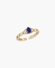 Macro view of a gold-plated S925 silver ring with a central teardrop-shaped blue lapis lazuli stone and two sparkling zircons on a textured band.