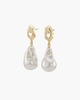 Close-up of gold geometric stud earrings with large irregular white baroque pearls featuring embedded tiny sparkling zircons.