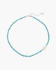 Top view of a natural turquoise beaded necklace featuring two irregularly shaped baroque pearls and silver lobster clasp on a white background.